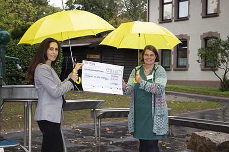 Eine Mitarbeiterin des Weinsberger Maschinen- und Anlagenbauers Vollert aus Weinsberg übergibt dem Klinikum am Weissenhof einen Spendenscheck. 